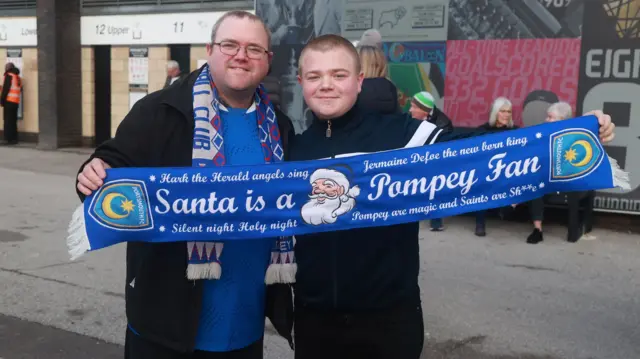 Portsmouth fans hold a festive scarf outside Pride Park