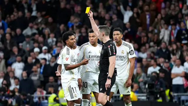 Rodrygo of Real Madrid (L) is shown a yellow card by referee, Alejandro Muniz