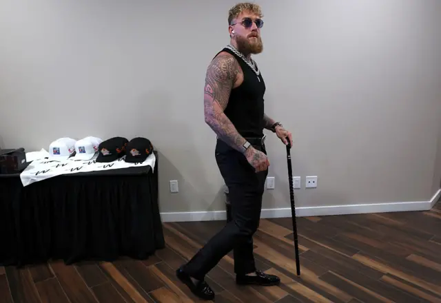 Jake Paul arrives in his dressing room wearing a black vest
