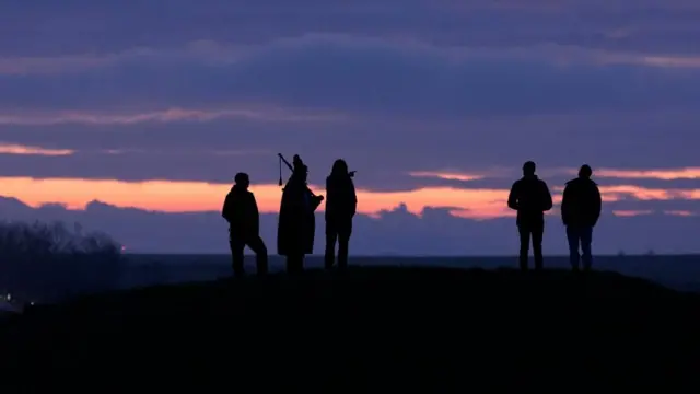 People (silhouetted) wait for sunrise during winter solstice celebrations at the Stonehenge.