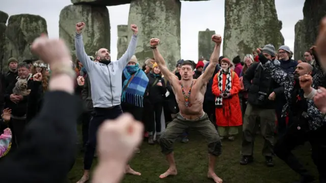 People practise yoga at the winter solstice celebrations during sunrise at Stonehenge stone circle