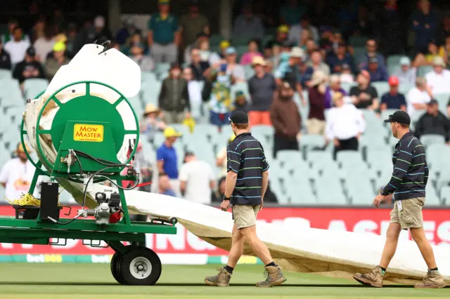 The groundstaff prepare to bring the covers on