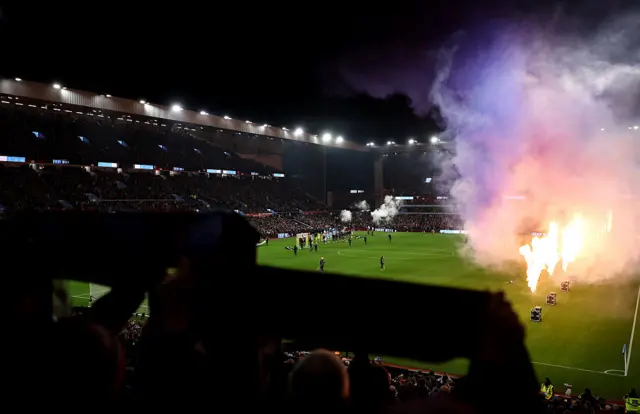 Fans hold their scarves aloft and pyrotechnics are set off as the teams line up prior to the Premier League match between Aston Villa and Manchester United at Villa Park on December 21, 2025 in Birmingham, England.