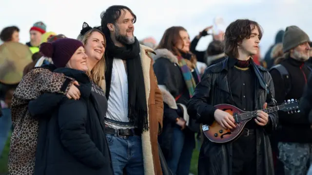 People embrace and one plays a mandolin