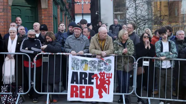 A crowd of people waiting behind barriers in Manchester