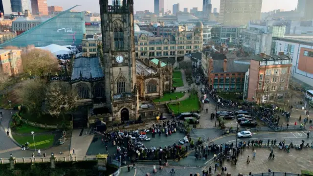 Birds-eye view of crowds gathering round Manchester Cathedral