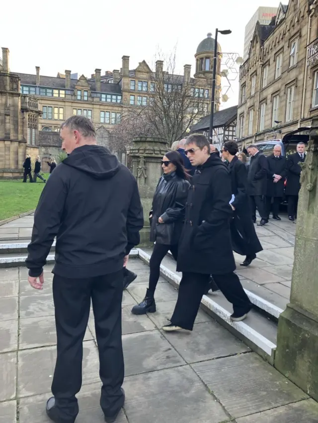 Liam Gallagher arriving at Manchester Cathedral. He's wearing a black coat