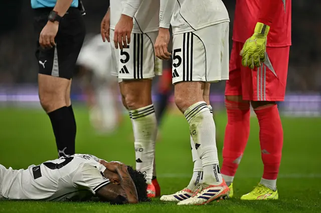 Fulham's Brazilian midfielder #22 Kevin (L) holds his neck as he lays on the pitch injured during the English Premier League football match between Fulham and Nottingham Forest at Craven Cottage