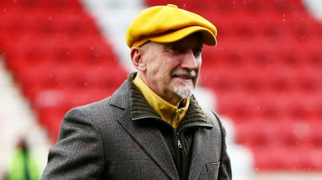 Ian Holloway, Swindon manager, wearing a yellow flat cap