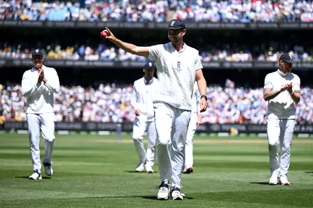Josh Tongue of England holds up the ball as he leaves the field