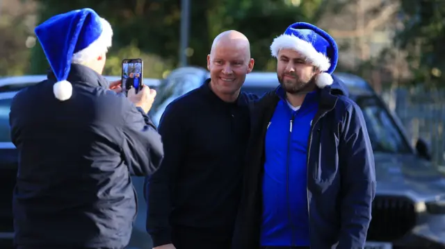 Sheff Wed manager Henrik Pedersen (middle) having his photo taken with a fan wearing a blue Santa hat by another fan wearing a blue Santa hat