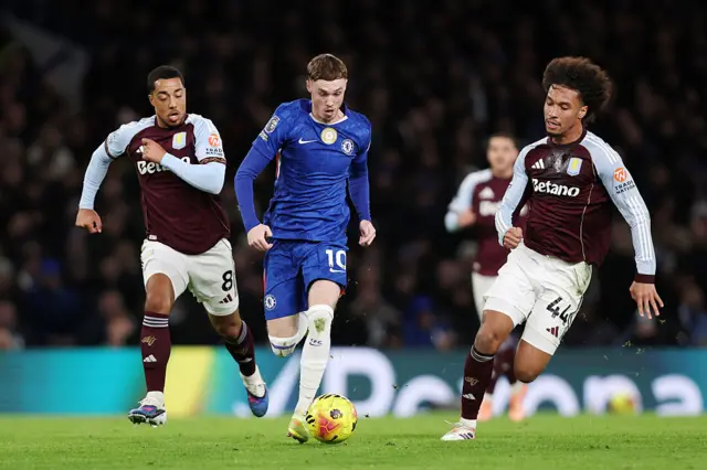 Cole Palmer of Chelsea runs with the ball whilst under pressure from Boubacar Kamara of Aston Villa during the Premier League match between Chelsea and Aston Villa at Stamford Bridge on December 27, 2025 in London, England.