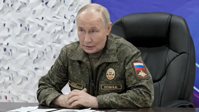 Putin in military camouflage clothing sitting in a leather chair