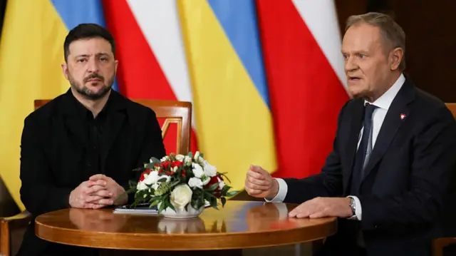 Zelensky sits next to Tusk at a table
