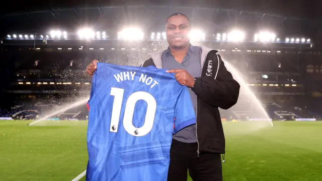 David Munyua holds up a Chelsea shirt