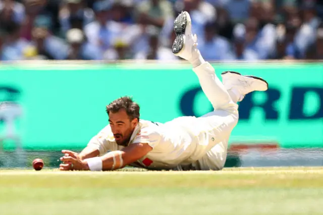 Mitchell Starc of Australia fields off his own bowling