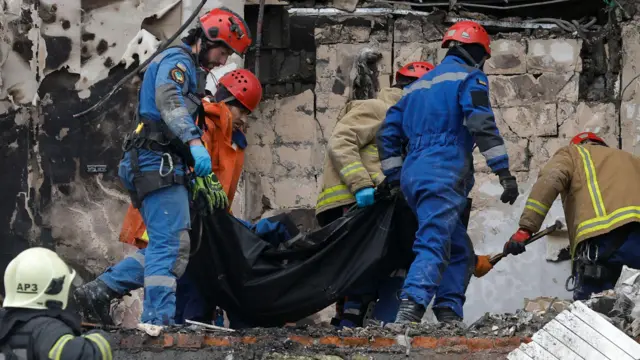Rescue workers carry a body bag