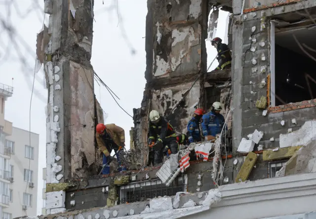 Members of Ukraine's fire service operate in Kyiv in a bombed out flat on a high floor of a residential building