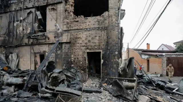A blackened building surrounded by crumbling debris