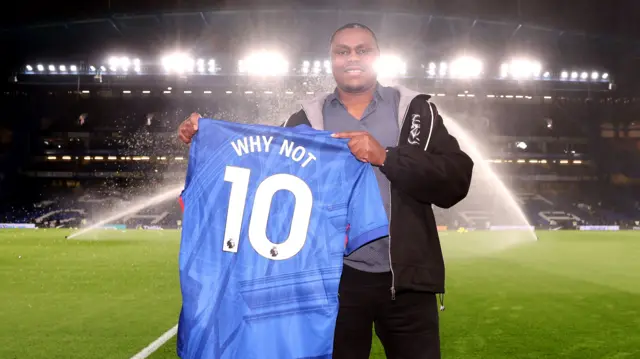David Munyua holds up a Chelsea shirt