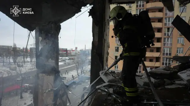 A firefighter stands in rubble of building