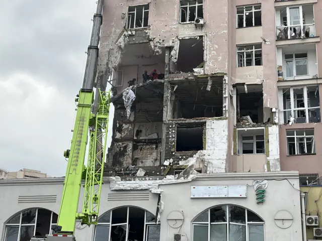 Rescuers work in building with huge chunk of exterior wall destroyed
