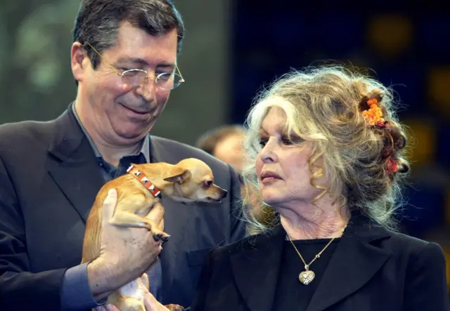 Bardot looks at a small dog being held by Levallois-Perret Patrick Balkany