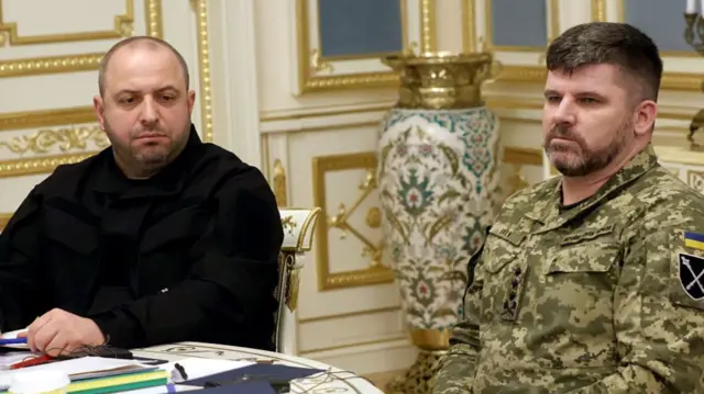 Two men, one in black and one in uniform)