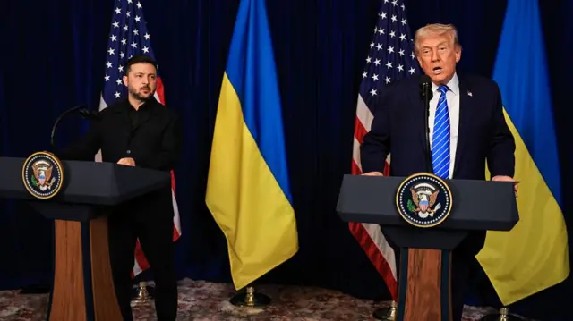 Trump speaking at podium as Zelensky looks at him from his own podium