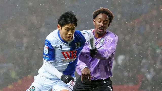 Blackburn forward Yuki Ohashi (left) and Sheffield Wednesday's Jamal Lowe battle for the ball at a rainy Ewood Park
