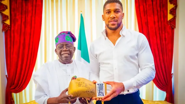 The President of Nigeria with Anothony Joshua holding a signed boxing glove