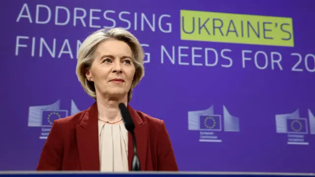 European Commission President Ursula von der Leyen standing in front of a wall that reads 'Addressing Ukraine's Financial Needs For 20[continues off-screen]'