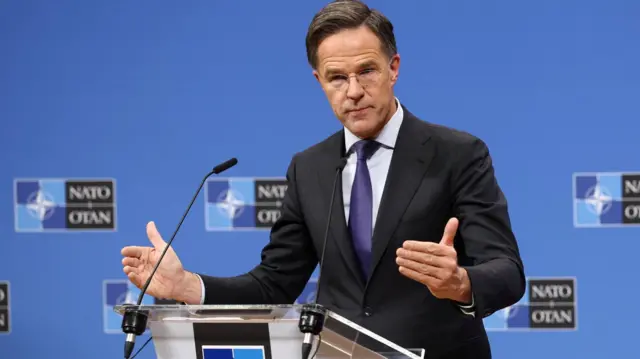 Mark Rutte in suit behind lectern, answering questions