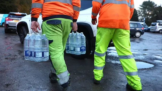 Volunteers from South-East Water assist members of the public load bottled water into their vehicles at a distribution point