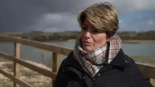 Emma Hardy wearing a black coat and a brown scarf.