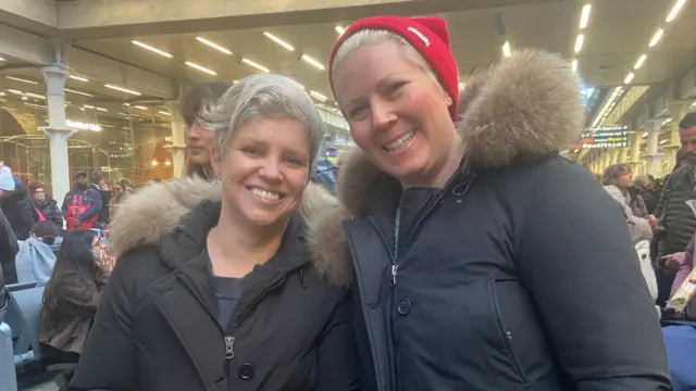 Haley Adams and Hannah Hagar at St Pancras. Both wear dark, hooded jackets.