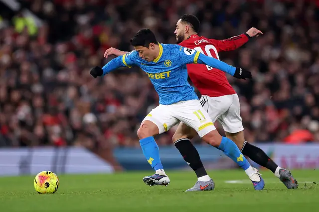 Hwang Hee-Chan battles for possession with Matheus Cunha