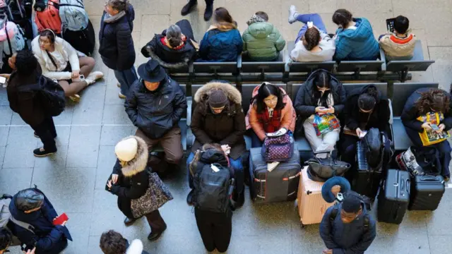 Passengers wait on the concourse at St Pancras, many with suitcases and winter coats