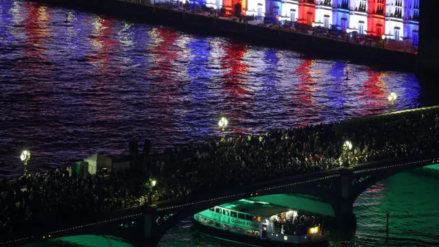 People are pictured gathered on a bridge in London, in front of the Houses of Parliament.