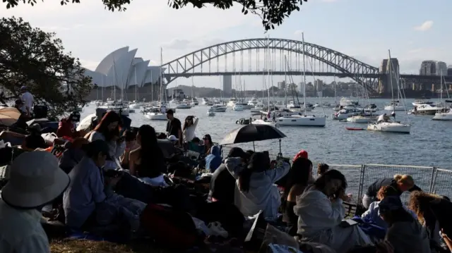 People sit at Mrs Macquaries Point overlooking the Sydney Opera House and the Sydney Harbour Bridge ahead of New Year's Eve fireworks, in Sydney, Australia, December 31, 2025.