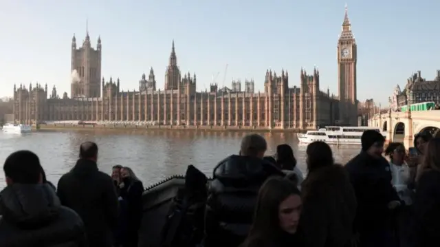 eople gather on Westminster Bridge across from the Houses of Parliament in London