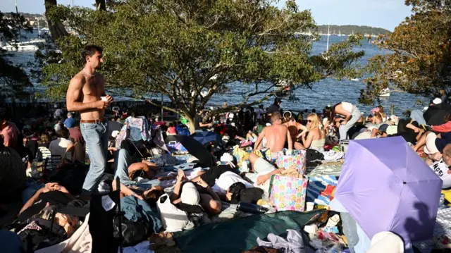 People sitting outside with the harbour behind them