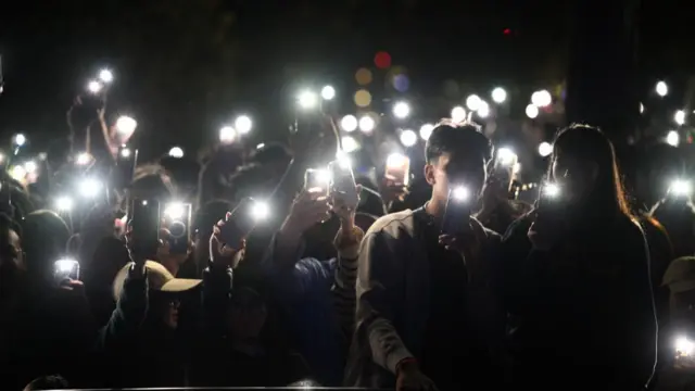 Spectators shine light from their mobile phones during a tribute to the victims of the Bondi attack