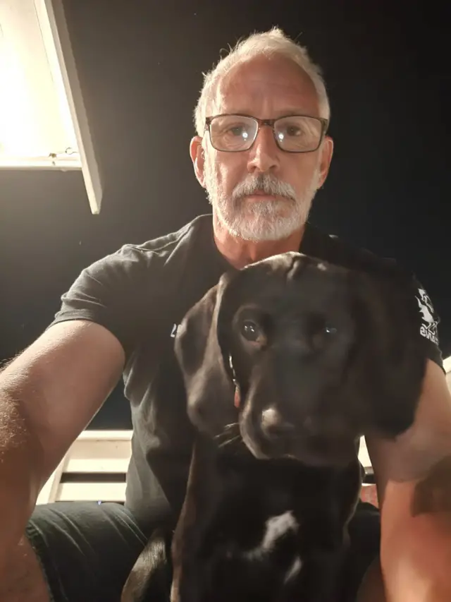 Andy Corson takes a selfie with Jess, a black puppy that is a cross between a Labrador and a Springer Spaniel
