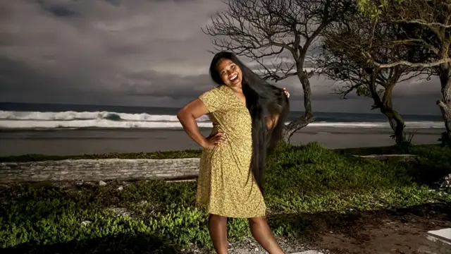 Woman in floral dress smiles for camera at beach during night