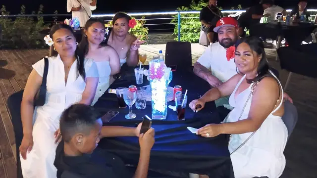 Group of people dressed in white at a table with drinks