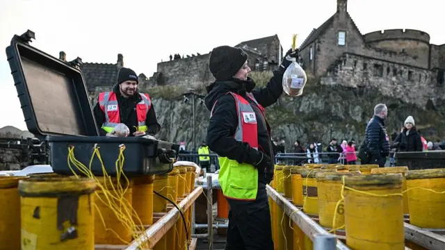 Pyrotechnicians Lynn Wiseman (C) and Sam Hutchinson (behind L) prepare New Year's fireworks around Edinburgh Castle ahead of the annual Hogmanay street party in Edinburgh on December 30, 2025, which culminates in a midnight fireworks display over the castle