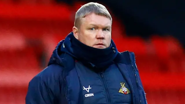 Doncaster manager Grant McCann wearing a coat and scarf standing in a football stadium
