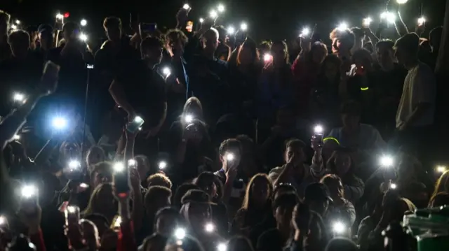 Spectators shine light from their mobile phones during a tribute to the victim's of the Bondi terror attack during the New Year's Eve Celebrations at Mrs Macquaries Point in Sydney, Australia, December 31, 2025.