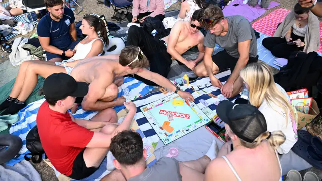 People play the board game Monopoly as they await a fireworks display in Sydney, Australia